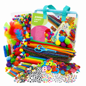 Colorful craft kit contents spilling from a clear bag, including pom-poms, feathers, pipe cleaners, beads, and scissors.