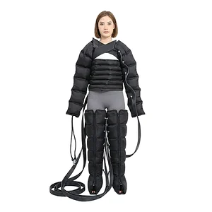 Woman wearing a black padded full-body harness with multiple straps and cords attached, standing against a white background.